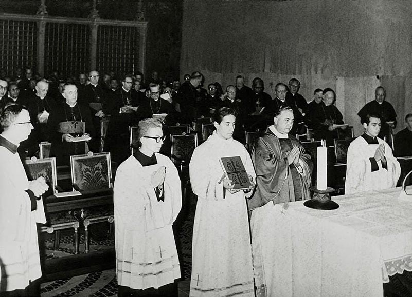 Das Photo aus der Sixtinischen Kapelle zeigt Erbuschif Bugnini, zwei Ministranten und einen Lektor unmittelbar vor Beginn der Messe an einem in der Sixtina aufgestellten „Volksaltar“.