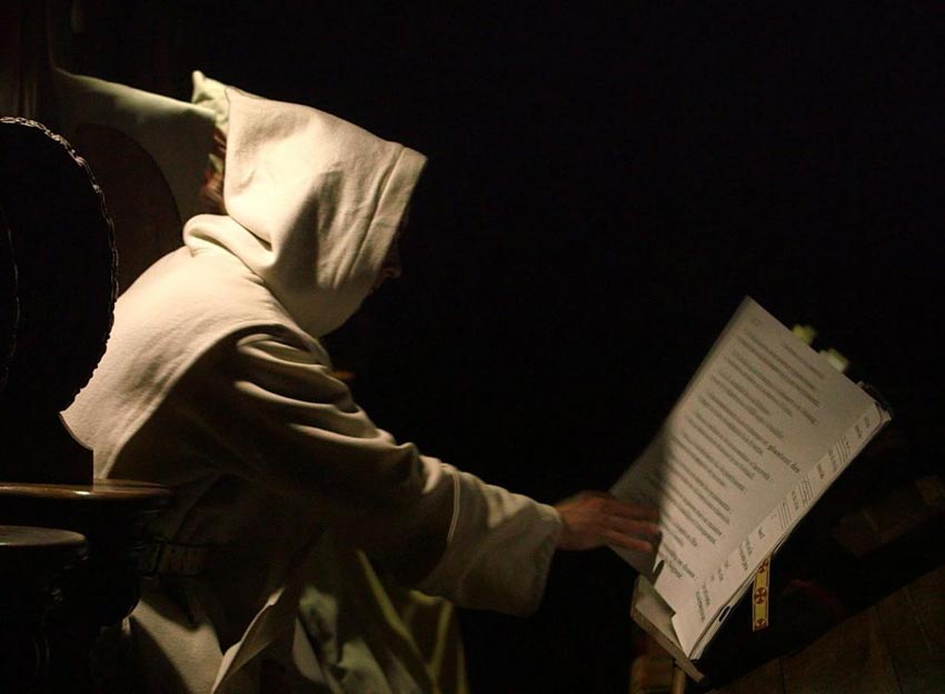 Nächtlicher Gottesdienste Im Kloster der Grand Chartreuse. <br>Bild: Webseite der Kartäuser https://chartreux.org/ Mönch beim nächtlichen Stundengebet am nur von einer Kerze erhellten Lesepult.