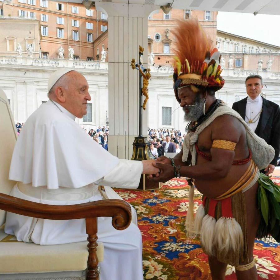 Das Bild wirft quälende Fragen auf: Sehen wir hier authentische Tradition oder Stereotypen aus dem nachkolonialen Bewußtsein? Und ist der Gast auch im Einbaum aus Australien gekommen, und vor allem: wo trägt er sein Handy?<br>Bild: Screenshot von Twitter/X Der in abenteuerlich erscheinender Stammestracht gekleidete Ehrengast reicht dem Papst die Hand
