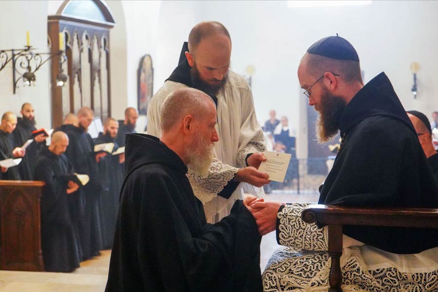 Der Gründer und bisherige Prior Folsom legt „in die Hände“ seines Nachfolgers Nivakoff das Gehorsamsversprechen ab.<br>Bild: Newsletter des Klosters; https://mailchi.mp/nursia/may_28_abbey Das Phot zeigt den Gründer und bisherigen Prior Folsom bei der Ablegung des Gehorsamsversprechens vor seinem Nachfolger Nivakof