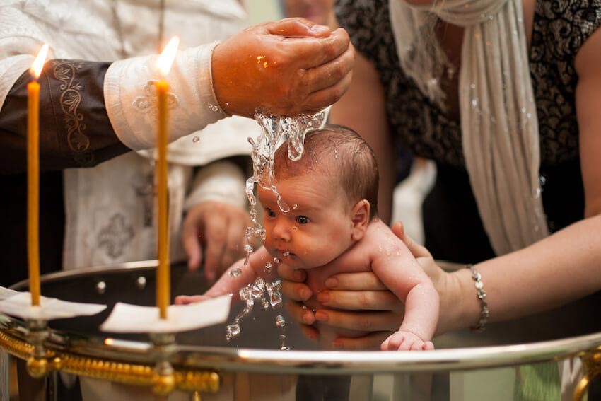 Die richtigen Worte sind das Wesentliche, aber auch beim Wasser sollte man nicht gar zu zimperlich sein. Die Kleinen stecken das weg. <br>Bild: www.greenvelope.com/blog/babys-baptism Der Priester übergießt den Kopf des Täuflings mit reichlich mit der Hand geschöpftem Wasser
