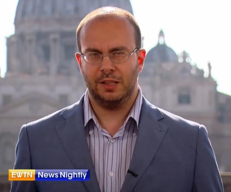 Porträtphoto von Andrea Gagliarducci aus einem Interview für EWTN vor der Kuppel des Petersdoms im Hintergrund.<br>Screenshot Youtube Seminaristen und Nuegeweihte im Kreise des Weihenden Bischofs